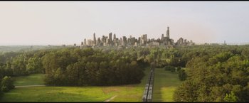 Movie still from “The Divergent Series: Insurgent” (2015), directed by Robert Schwentke – A view of a city from a distance with train tracks running parallel to it; Extreme Wide shot, High angle