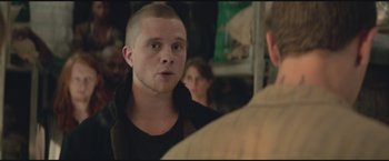 Movie still from “The Divergent Series: Insurgent” (2015), directed by Robert Schwentke – A man with a shaved head talking to another man in a crowd; Close Up shot, Over the shoulder angle