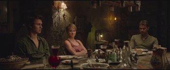 Movie still from “The Divergent Series: Insurgent” (2015), directed by Robert Schwentke – A woman sitting at a dinner table in a dimly - lit room; Medium shot, Over the shoulder angle