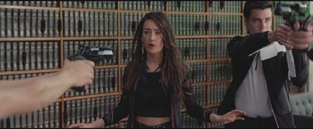 Movie still from “The Divergent Series: Insurgent” (2015), directed by Robert Schwentke – A woman in a black top is standing in front of a book shelf; Medium shot, High angle