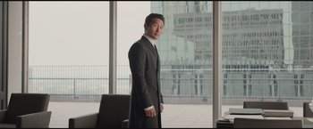 Movie still from “The Divergent Series: Insurgent” (2015), directed by Robert Schwentke – A man in a suit standing in front of a large window; Medium shot, Over the shoulder angle