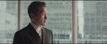 Movie still from “The Divergent Series: Insurgent” (2015), directed by Robert Schwentke – A person wearing a suit near a window; Close Up shot, Over the shoulder angle