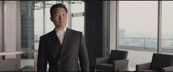 Movie still from “The Divergent Series: Insurgent” (2015), directed by Robert Schwentke – A man in a suit standing in front of a window; Medium shot, Low angle