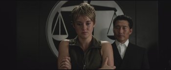 Movie still from “The Divergent Series: Insurgent” (2015), directed by Robert Schwentke – A woman with short blonde hair standing in front of a man; Medium shot, Over the shoulder angle