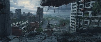 Movie still from “The Divergent Series: Insurgent” (2015), directed by Robert Schwentke – An aerial view of a destroyed city with buildings and trees; Extreme Wide shot, High angle