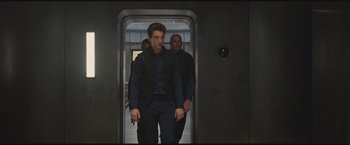 Movie still from “The Divergent Series: Insurgent” (2015), directed by Robert Schwentke – A man walking down a hallway with two other men behind him; Medium shot, Low angle