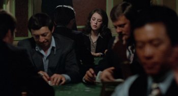 Movie still from “The Driver” (1978), directed by Walter Hill – A group of people sitting at a table playing cards; Medium shot, Over the shoulder angle