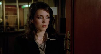 Movie still from “The Driver” (1978), directed by Walter Hill – A woman with long hair wearing a black jacket; Close Up shot, Over the shoulder angle