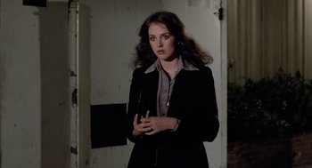 Movie still from “The Driver” (1978), directed by Walter Hill – A woman in a black jacket standing next to a door; Medium shot, Over the shoulder angle