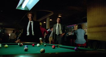 Movie still from “The Driver” (1978), directed by Walter Hill – A group of people standing around a pool table; Medium shot, Over the shoulder angle