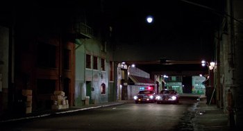 Movie still from “The Driver” (1978), directed by Walter Hill – A police car parked on the side of the road at night; Extreme Wide shot, High angle