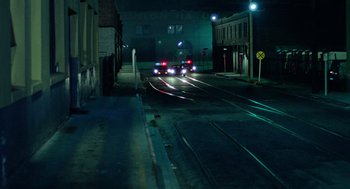 Movie still from “The Driver” (1978), directed by Walter Hill – A car driving down a street at night; Extreme Wide shot, High angle