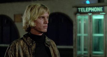 Movie still from “The Driver” (1978), directed by Walter Hill – A man with long blonde hair wearing a black shirt; Close Up shot, Low angle
