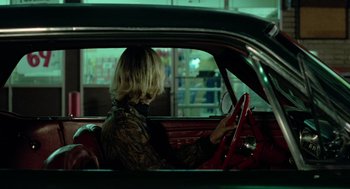 Movie still from “The Driver” (1978), directed by Walter Hill – A woman sitting in a car in the back of a car; Medium shot, Over the shoulder angle