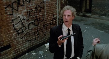 Movie still from “The Driver” (1978), directed by Walter Hill – A man in a suit and tie holding a cell phone; Medium shot, Low angle