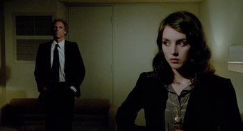 Movie still from “The Driver” (1978), directed by Walter Hill – A man and a woman standing next to each other in a room; Medium shot, Over the shoulder angle