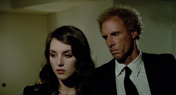 Movie still from “The Driver” (1978), directed by Walter Hill – A man and a woman standing next to each other in a room; Close Up shot, Over the shoulder angle