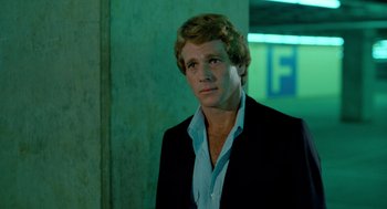 Movie still from “The Driver” (1978), directed by Walter Hill – A man wearing a suit and tie standing in a room; Close Up shot, Over the shoulder angle