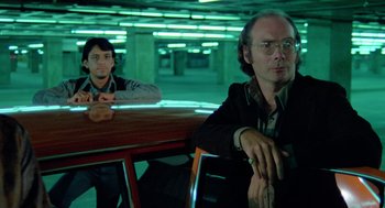 Movie still from “The Driver” (1978), directed by Walter Hill – Two men sitting at a table in a room; Medium shot, Low angle