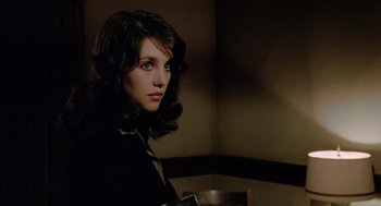 Movie still from “The Driver” (1978), directed by Walter Hill – A woman in a black suit is holding a black purse; Close Up shot, Over the shoulder angle