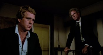 Movie still from “The Driver” (1978), directed by Walter Hill – A man in a suit and tie next to another man in a suit and tie; Medium shot, Low angle