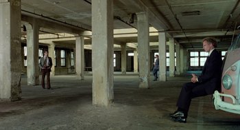 Movie still from “The Driver” (1978), directed by Walter Hill – A man walking in an empty room with pillars; Extreme Wide shot, High angle