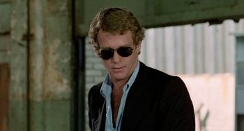 Movie still from “The Driver” (1978), directed by Walter Hill – A person wearing a suit and sunglasses; Close Up shot, Over the shoulder angle