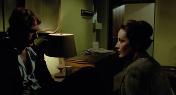 Movie still from “The Driver” (1978), directed by Walter Hill – A woman sitting on a couch in front of a mirror; Medium shot, Over the shoulder angle