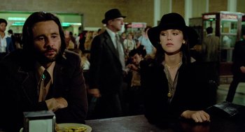 Movie still from “The Driver” (1978), directed by Walter Hill – Two people sitting at a table in front of a group of people; Medium shot, Low angle