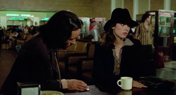 Movie still from “The Driver” (1978), directed by Walter Hill – Two people sitting at a table with a cup of coffee; Medium shot, Over the shoulder angle
