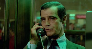 Movie still from “The Driver” (1978), directed by Walter Hill – A man talking on a phone while wearing a suit and tie; Close Up shot, Low angle