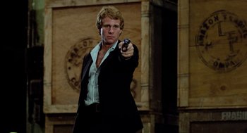 Movie still from “The Driver” (1978), directed by Walter Hill – A man holding a gun while wearing a suit and tie; Medium shot, Low angle