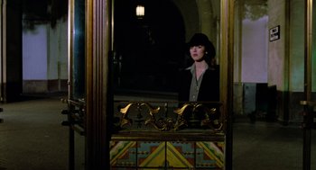 Movie still from “The Driver” (1978), directed by Walter Hill – A woman wearing a black hat looking out of a window; Wide shot, Low angle