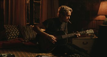 Movie still from “Euphoria” (2019), created by Sam Levinson – A man sitting on a bed playing a guitar; Medium shot, Over the shoulder angle