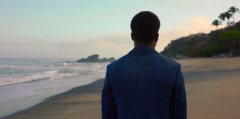 A man standing on the beach looking out at the ocean