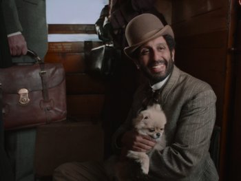 Movie still from “The Electrical Life of Louis Wain” (2021), directed by Will Sharpe – A man holding a small dog in his arms; Medium shot, Over the shoulder angle