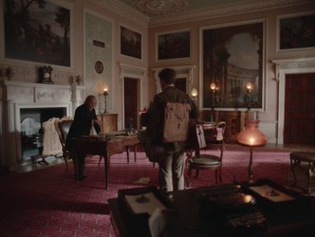 Movie still from “The Electrical Life of Louis Wain” (2021), directed by Will Sharpe – Two people are sitting at a table in a large room; Wide shot, Low angle