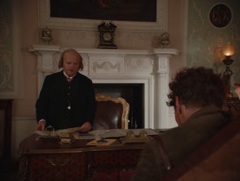 Movie still from “The Electrical Life of Louis Wain” (2021), directed by Will Sharpe – A man standing in front of a man sitting in front of a fireplace; Medium shot, Over the shoulder angle