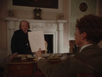 Movie still from “The Electrical Life of Louis Wain” (2021), directed by Will Sharpe – A man holding up a drawing in front of a man in a suit; Medium shot, Over the shoulder angle