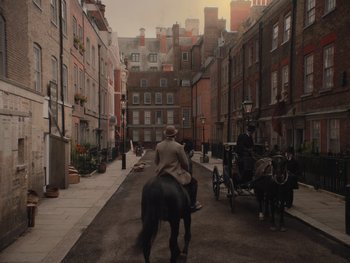 Movie still from “The Electrical Life of Louis Wain” (2021), directed by Will Sharpe – A man riding a horse drawn carriage down a street; Extreme Wide shot, High angle