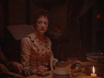 Movie still from “The Electrical Life of Louis Wain” (2021), directed by Will Sharpe – A woman sitting at a table with a tea pot in front of her; Medium shot, High angle