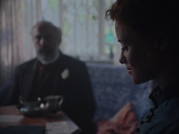 Movie still from “The Electrical Life of Louis Wain” (2021), directed by Will Sharpe – A woman sitting at a table in front of an older man; Medium shot, Over the shoulder angle