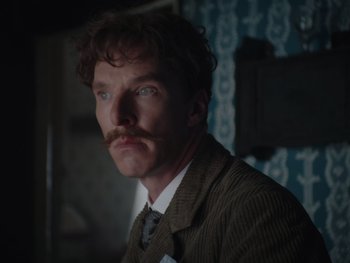 Movie still from “The Electrical Life of Louis Wain” (2021), directed by Will Sharpe – A man in a suit and tie with a fake mustache; Close Up shot, Over the shoulder angle