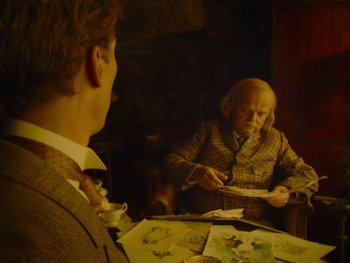 Movie still from “The Electrical Life of Louis Wain” (2021), directed by Will Sharpe – An old man sitting in front of a man in a suit; Medium shot, Over the shoulder angle