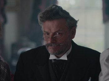 Movie still from “The Electrical Life of Louis Wain” (2021), directed by Will Sharpe – An older man with a mustache and a beard; Close Up shot, Over the shoulder angle
