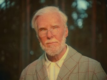 Movie still from “The Electrical Life of Louis Wain” (2021), directed by Will Sharpe – An old man with a white beard wearing a suit; Close Up shot, High angle