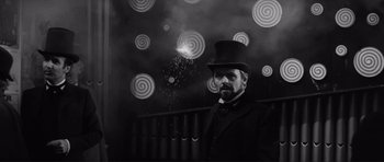 Movie still from “The Elephant Man” (1980), directed by David Lynch – A black and white photo of a man wearing a top hat; Medium shot, Low angle