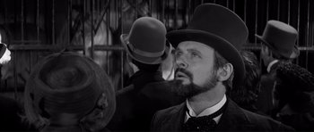 Movie still from “The Elephant Man” (1980), directed by David Lynch – A man with a beard wearing a top hat; Close Up shot, Over the shoulder angle