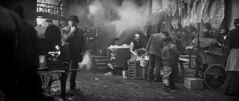 Movie still from “The Elephant Man” (1980), directed by David Lynch – A group of people standing around a building; Wide shot, High angle