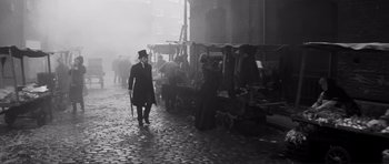 Movie still from “The Elephant Man” (1980), directed by David Lynch – A man in a top hat walking down a street; Wide shot, High angle